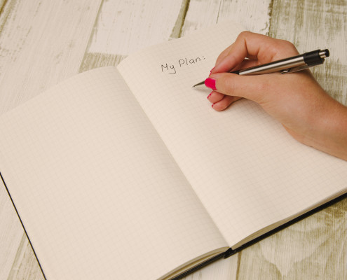 Female hand holding a pen and writing a plan in a planner