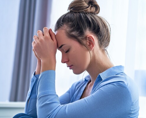 Sad lonely depressed hopeless woman with folded hands lost in thoughts thinking about life and worried about emotional problems during depression